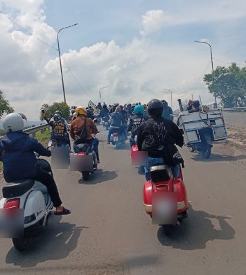 Rombongan Vespa klasik berkendara beriringan di jalan raya